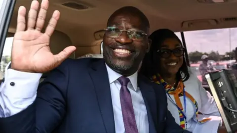 AFP Charle Ble Goude, former right-hand man to ex-president Laurent Gbagbo waves from his car upon his arrival at Felix-Houphouet Boigny airport in Abidjan on November 26, 2022