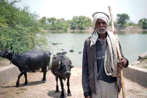 Ankit Srinivas Rameshwar Yadav, a buffalo rearer, wears a shawl and heavy winter clothes despite the 46°C heat