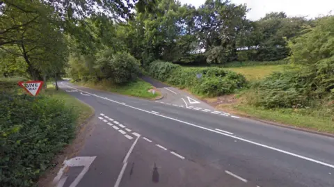 A Google street view image of a crossroads on a main road in a rural area. 