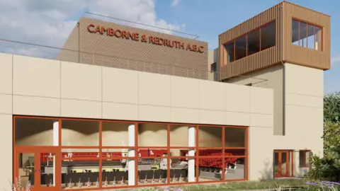 Create Design South West A picture of the front of the proposed new building for boxing. It is a rectangular cream coloured building with a large window at the front and a tower on the right hand side.
