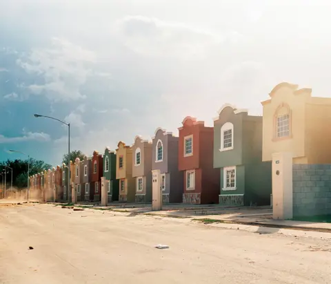 Alejandro Cartagena A photo by Alejandro Cartagena showing a line of colourful homes on an empty street