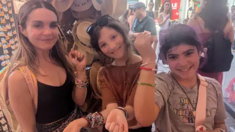 Seema Shirazi Three girls standing in shop showing friendship bracelets 