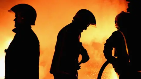 Getty Images fire crews in silhouette against a fire