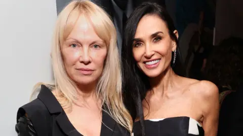 Getty Images Pamela Anderson and Demi Moore attend W Magazine's Annual Best Performances Party at Chateau Marmont on January 4 2025 in Los Angeles. Anderson is wearing a black jacket and has long blonde hair. Moore has long black hair and is wearing a strapless black and white gown.