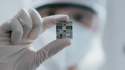 Getty Images A female engineer inspects a wafer chip.