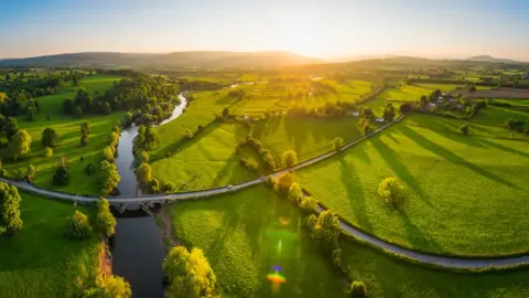 Getty Images Sunset illuminating green pasture, agricultural crops, farms, villages and the distant mountains beyond the River Usk