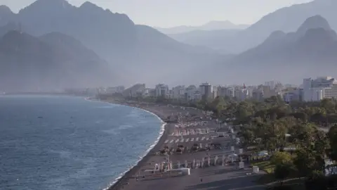 Chris McGrath/Getty Images People walk on a near empty Konyaalti beach during a weekend lockdown on 06 June, 2021 in Antalya, Turkey.