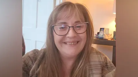 Mel Collins Mel Collins smiles at the camera. She has long light brown hair and wears a cream coloured top with brown lines on it. 