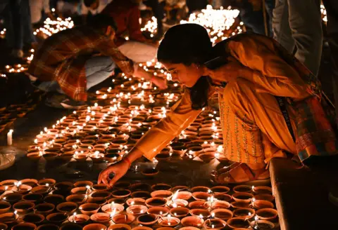 Getty Images People light earthen lamps on the banks of Sarayu River during a program on the eve of Diwali on November 11, 2023 in Ayodhya