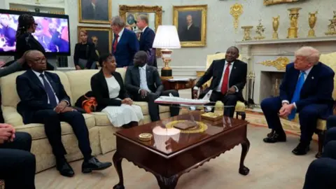 People in the Oval Office watch a video. 