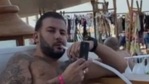 A topless image of Harding at a bar smoking a Shisha pipe