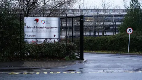 PA Media The outside of Bristol Brunel Academy. The building is surrounded by a metal fence. There is a white sign at the entrance.