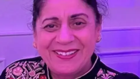 Family handout A picture of Pulvinder Dhillon, who has long hair tied back and is wearing gold earrings. She is smiling for the camera.