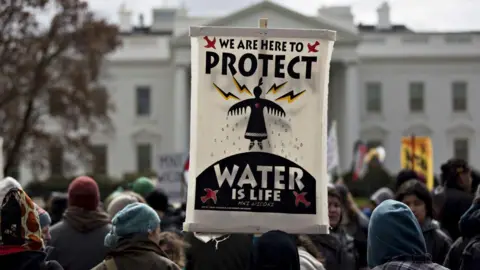 A demonstrator holds a "Water Is Life" sign in front of the White House during a protest against the Dakota Access Pipeline (DAPL) in Washington, D.C., U.S., on Friday, March 10, 2017