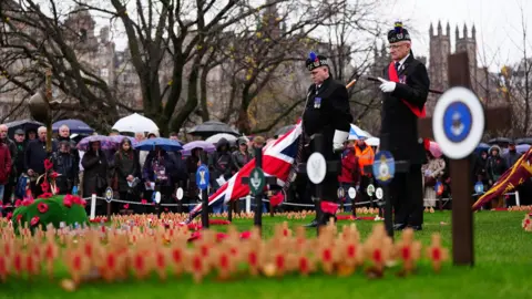 Veterans marked the silence in front of the Scott Monument overlooking a field of poppy's in Edinburgh, standing in old military uniforms as a crowd of onlookers pay their respects.