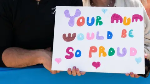 PA Media A sign photographed in the crowd reads: "You mum would be so proud." The letters are written in felt tip and each letter is multi-coloured. 