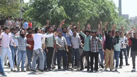 Hindustan Times via Getty Images Workers shout slogans during protest over wage hike demands at Noida Phase 2 industrial area on April 13, 2026 in Noida, India