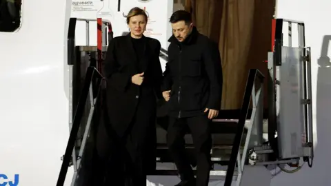 PA Media/Clodagh Kilcoyne Volodymyr Zelensky and his wife Olena Zelenska disembark from plane stairs towards the runway at Dublin Airport. On the side of the plane is a yellow and blue Ukrainian symbol.