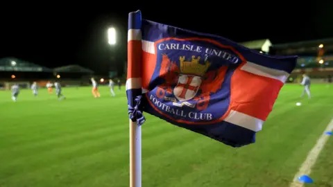 PA Media A Carlisle United corner flag with players training in the background