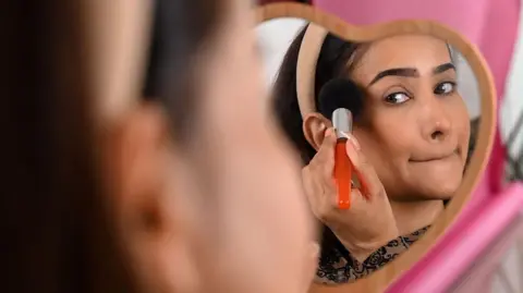 In this photo taken on March 17, 2023, social media influencer and make-up artist Faby does her make-up while going live on her YouTube channel in Mumbai.
