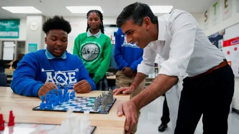 Reuters Rishi Sunak watches a child playing chess on a visit to a US school in Washington