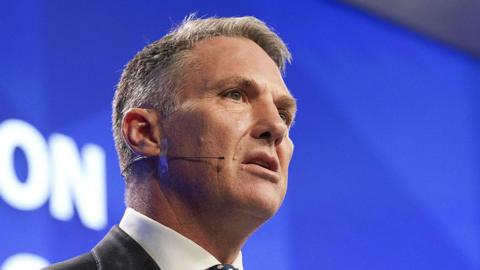 Richard Marles addresses a crowd while on stage and wearing a wireless microphone pasted to the side of his face