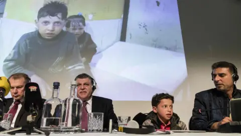 AFP Russian officials at a press conference, alongside a boy pictured in the aftermath of the attack