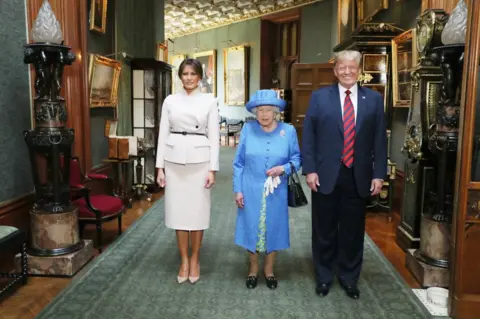 PA Queen Elizabeth II stands with US President Donald Trump and his wife, Melania, in the Grand Corridor during their visit to Windsor Castle