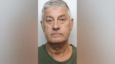 South Yorkshire Police A police mugshot of a man with short grey hair wearing a green t-shirt.