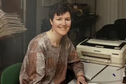 A woman at a desk taken. The image was taken in the early 1990s.