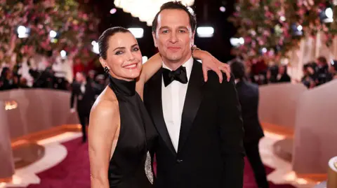 Getty Images Rhys and Keri in a black tie formal wear on the red carpet, both smiling for the camera. 