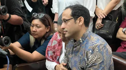BBC/Haryo Wirawan Nadiem's wife clutched his arm as they entered the courtroom on Tuesday morning 