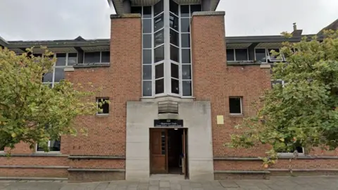 Isle of Wight Crown Court is a brick building with a stone-framed main entrance beneath a large window.