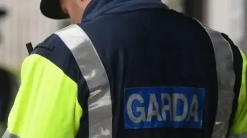 Police officer in yellow and blue jacket with Garda label on the back