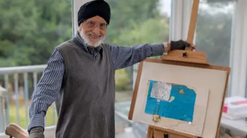 BBC Sardul Gill, inside his house, stood beside one of his pictures, which consists of a rectangle of blue paper with a rectangle of foil on top
