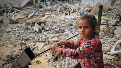 A girl stands among the rubble of buildings destroyed by Israeli air strikes in in Khan Yunis, the Gaza Strip. Photo: 17 November 2024