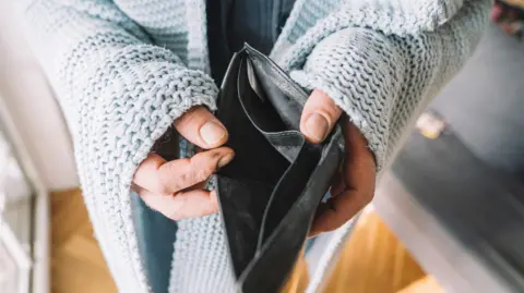 Hands of man wrapped in blanket holding empty wallet 