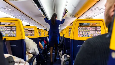 Ryanair flight attendant wearing the airline's blue uniform on a plane