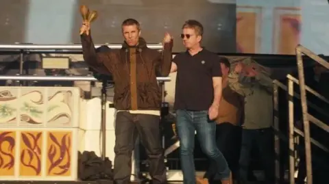 Liam Gallagher holds a pair of maracas and Noel's hand as they come on stage at Friday's concert in Manchester