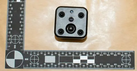 Metropolitan Police spy camera shown in evidence next to tape measure