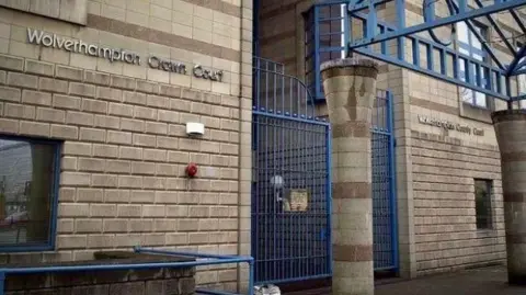 A brick building with a blue gate. Lettering on the wall reads "Wolverhampton Crown Court".