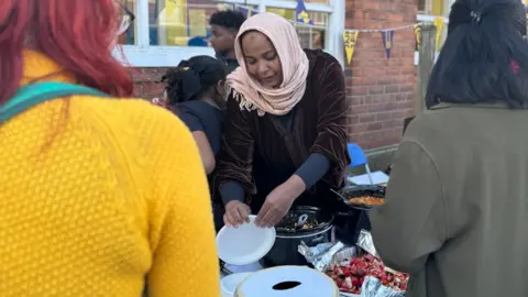 Woman in head wrap serving food at event