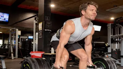 Supplied/ Dr Michael Mrozinski Dr Michael Mrozinski deadlifting at the gym, wearing a grey singlet 