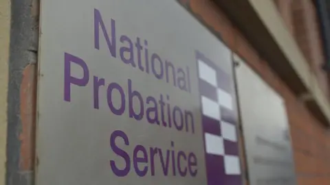 Getty Images A sign with the logo of the National Probation Service written on it, attached to a red brick wall.