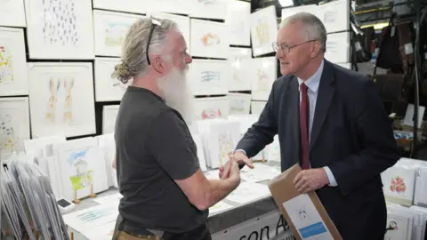 PA Media Northern Ireland Secretary Hilary Benn shakes hands with a market trader during a visit to St George's Market in Belfast