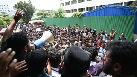 Getty Images A man speaks into a megaphone in front of a crowd of protesters