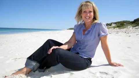 Nicki Chapman is sitting on a sandy beach in Perth, Western Australia. 