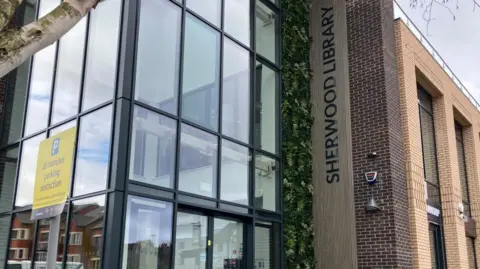 Glass corner building with black grid windows. 