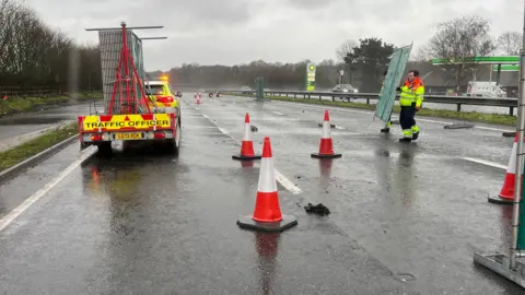 The closure on the A3 Northbound Ripley Bypass. A highways worker can be seen in the image alongside several cones and a traffic vehicle. 
