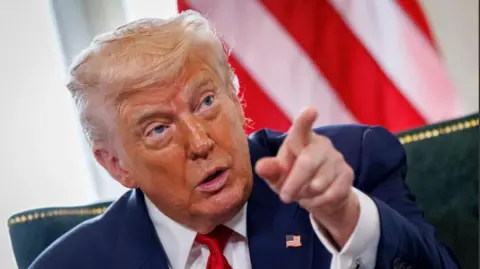 EPA Donald Trump with tanned orange face and wavy white hair points at camera in front of US flag